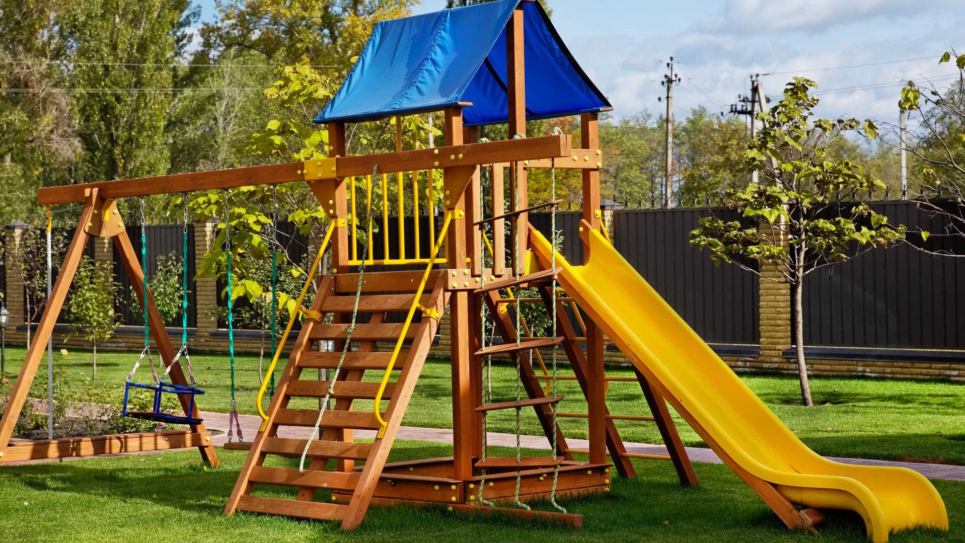 Spielturm aus Holz mit Rutsche und Schaukel in einem Garten