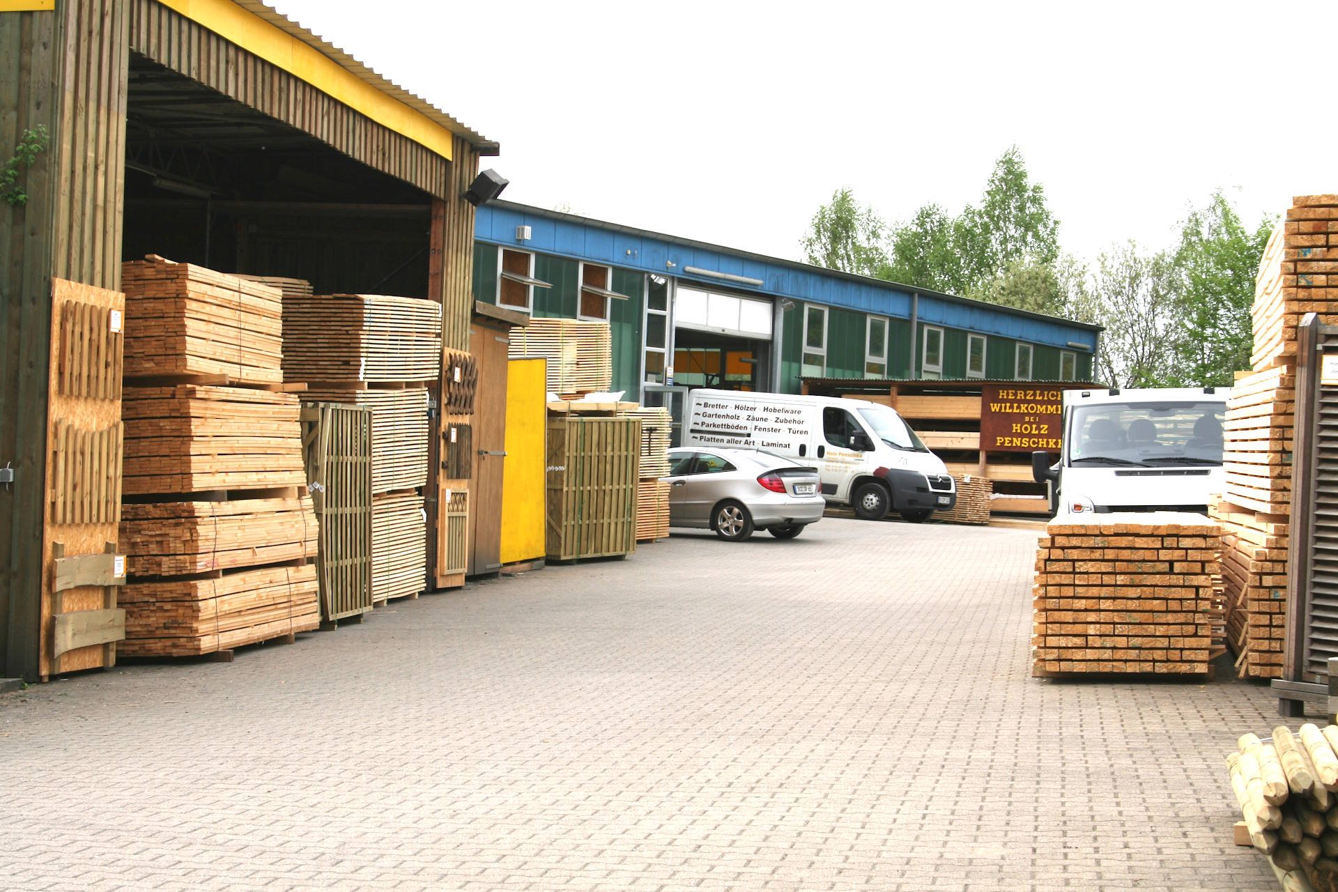 Holzhandel in Bochum mit überdachtem Holzlager, gestapeltem Schnittholz und Lieferfahrzeugen