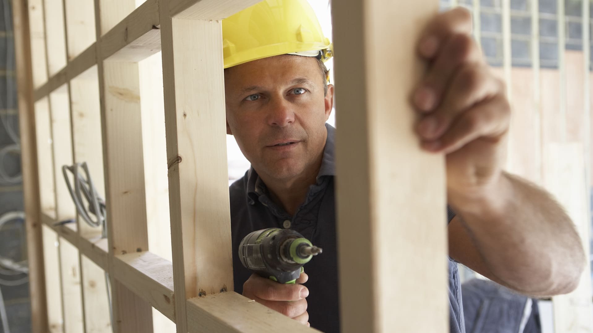 Bauholz und Konstruktionsvollholz: Handwerker montiert eine Holzkonstruktion aus Kanthölzern